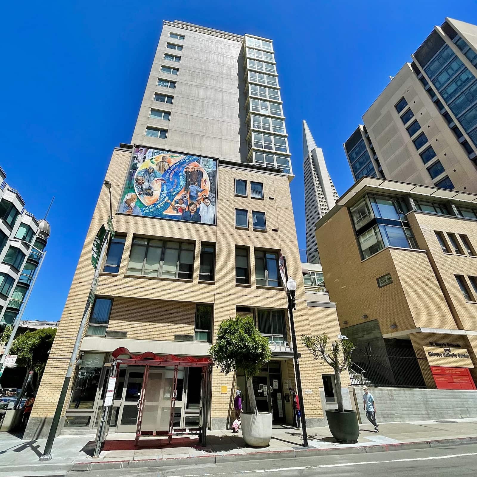 A tall apartment complex in a city setting with a mural showing activists demonstrating.