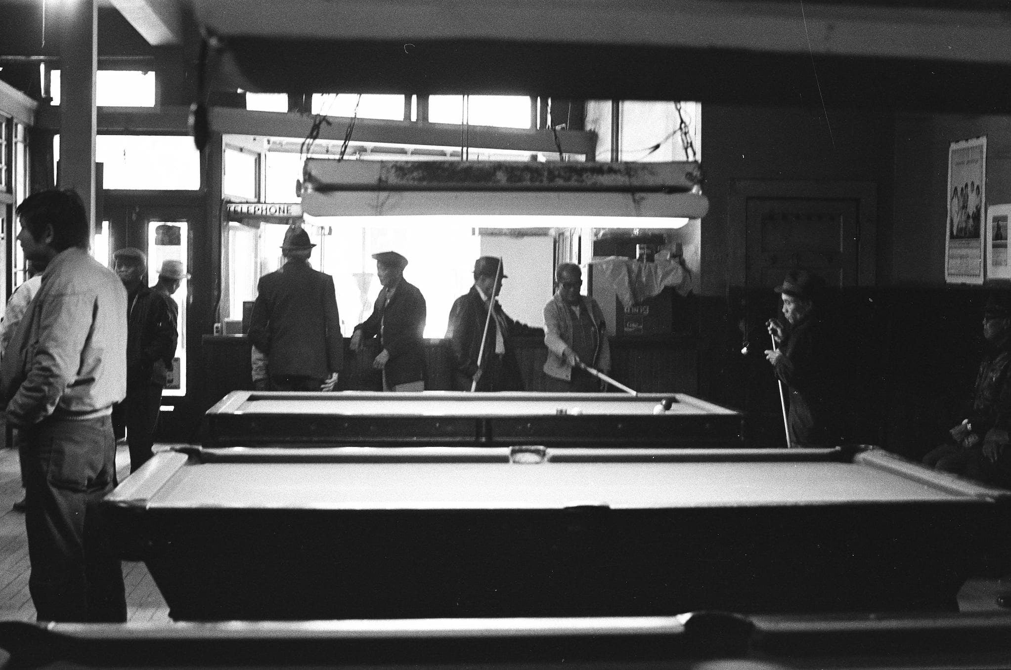 I-Hotel tenants gather in interior courtyard. Two tenants stand with watering cans next to plant beds. Another tenant stands in open window.
