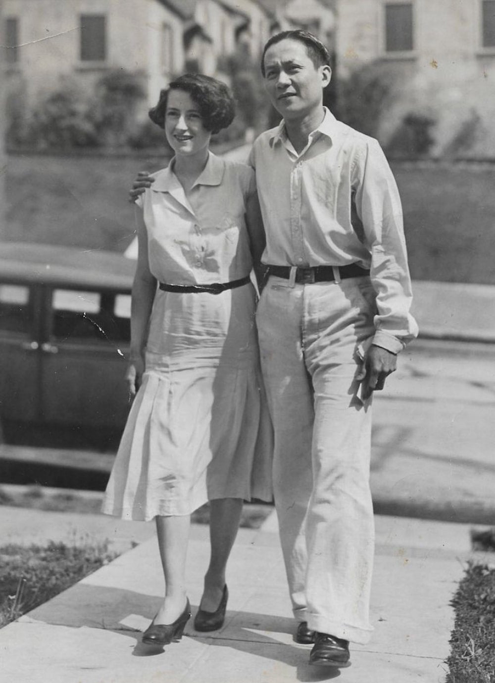 Salvador Roldan, a Filipino immigrant, and Marjorie Rogers, a white Englishwoman, dressed in semi-formal attire stand on a concrete pathway.