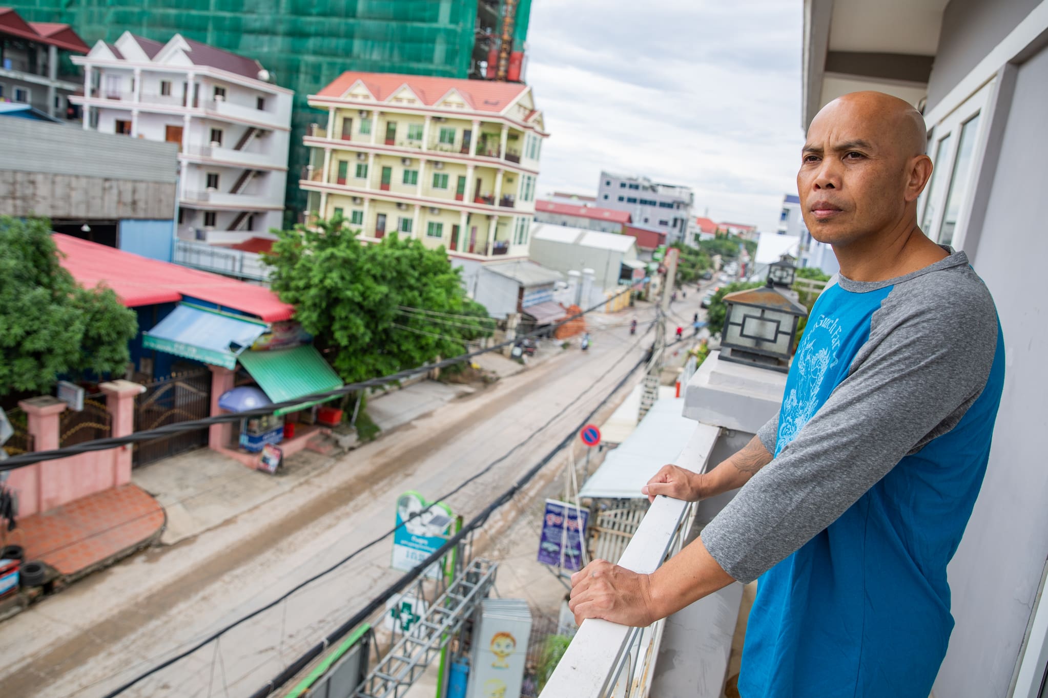 Former child refugee Phoeun You stands at his balcony overlooking Sen Sok in Phnom Penh, Cambodia after being deported from the US without warning.