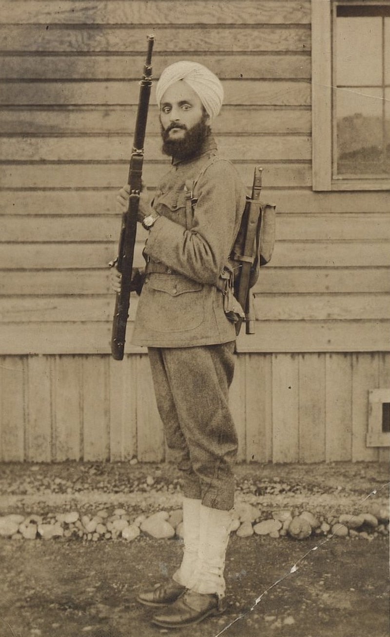 Bhagat Singh Thind, a Sikh man, in his U.S. Army uniform and turban, standing at attention with his rifle and gear.