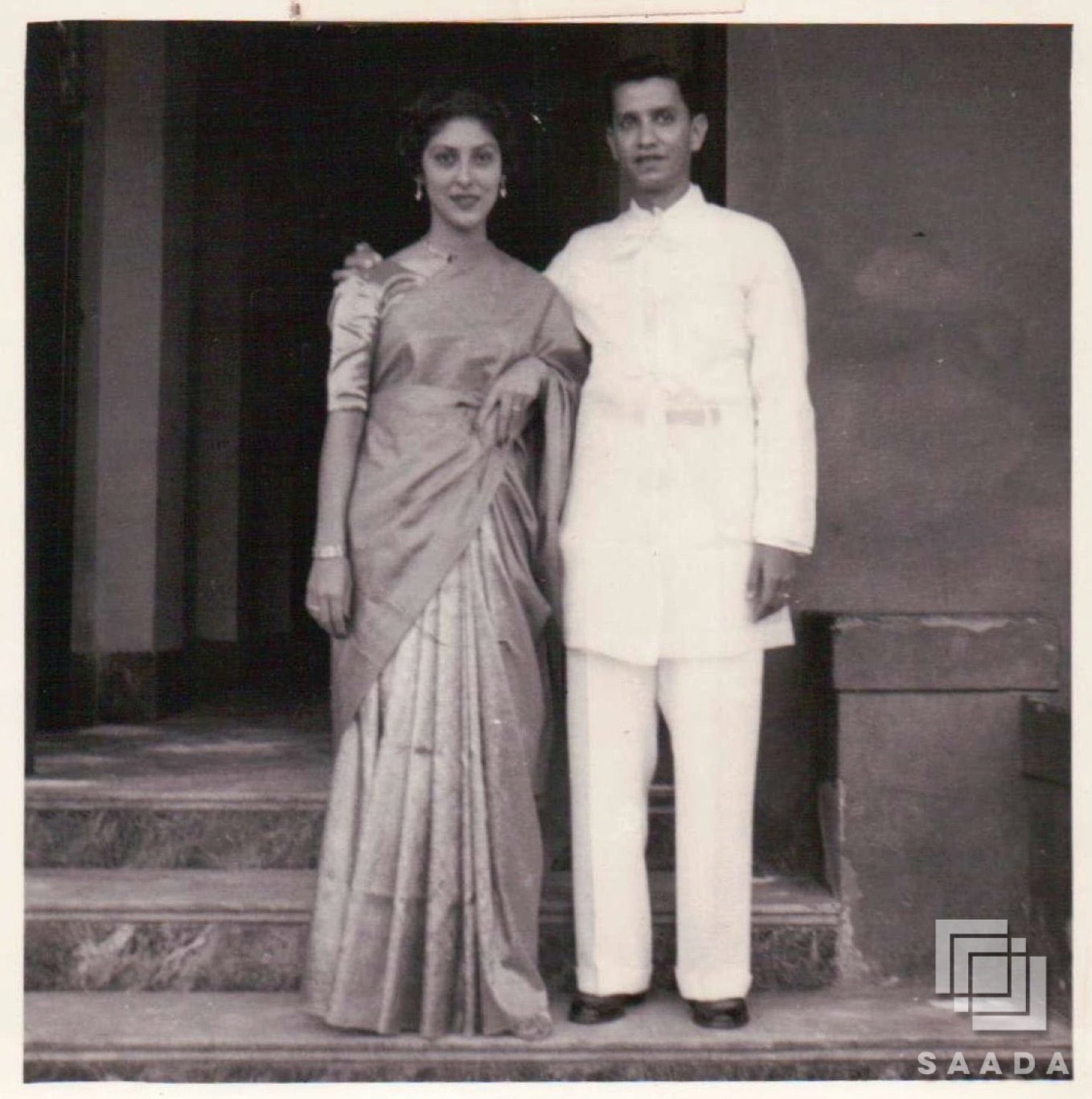 Punjabi Mexican couple Amelia Singh Netervala and Minoo Netervala at a wedding. She is dressed in a saree and he in a white sherwani and trousers.