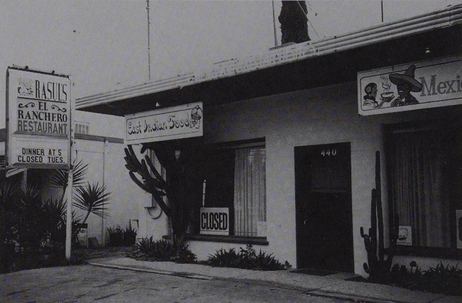 The facade and entrance for Rasul’s El Ranchero Restaurant. Two other signs that hang by the front door advertise East Indian and Mexican Food.