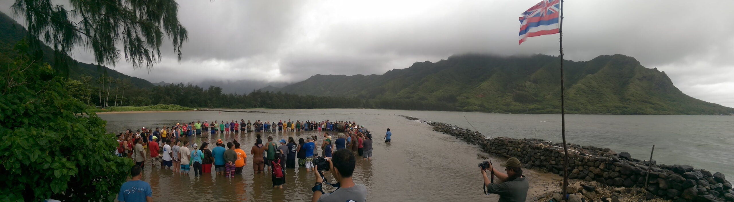 Cloudy, gray skies gather above as people of the KUA's E Alu Pū network stand in a circle in the Huilua Fishpond for a closing ceremony.