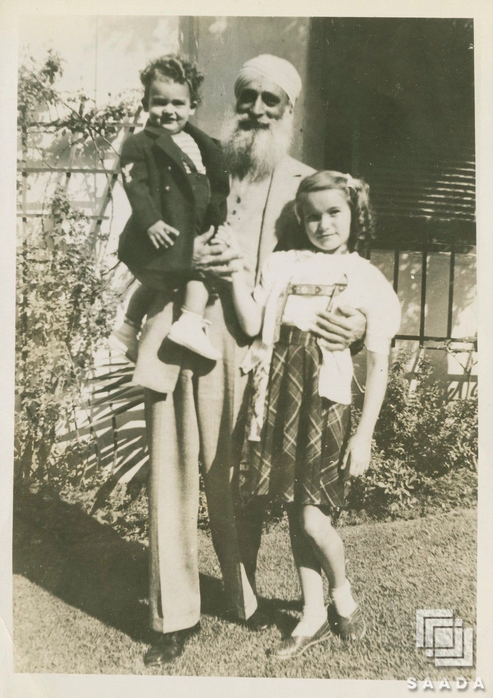 Bhagat Singh Thind, a Sikh man, holding his children in Toledo, Ohio. They are dressed in formal clothing and smiling.