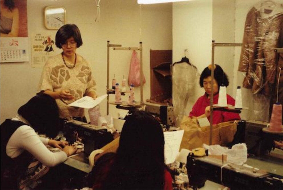 Labor organizer May Chen stands and distributes leaflets to workers seated in front of their work stations.