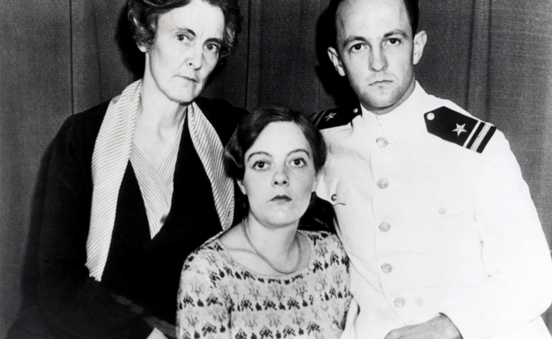 Thalia Massie enveloped by her husband and mother. All look grim. Her husband wears his service uniform.