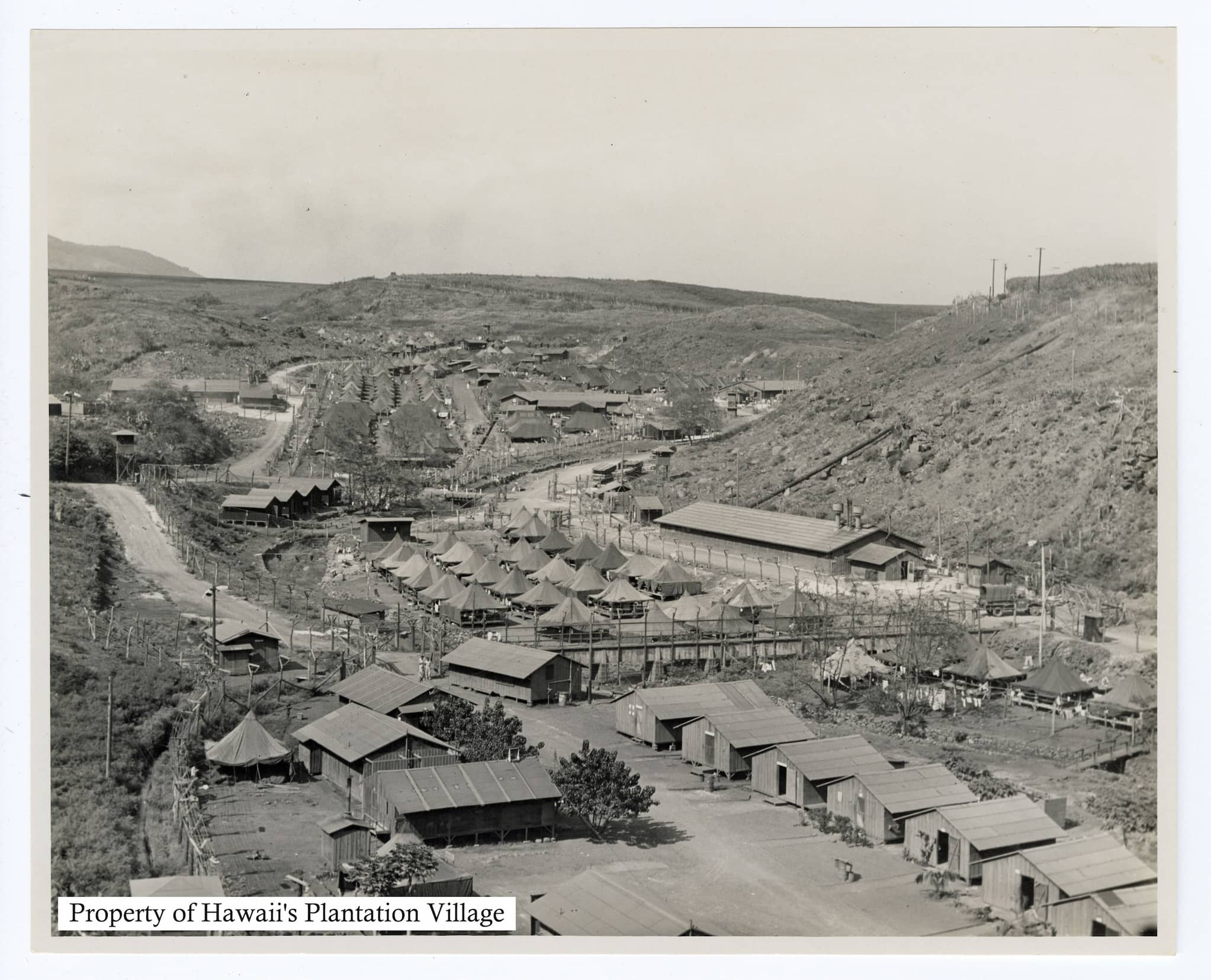 Rows of ramshackle huts span alongside the base of a mountain.