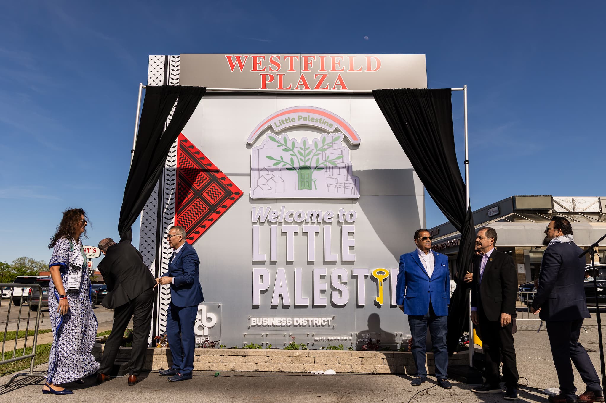 Men in suits gather in front of the Westfield Plaza sign to reveal the new name.