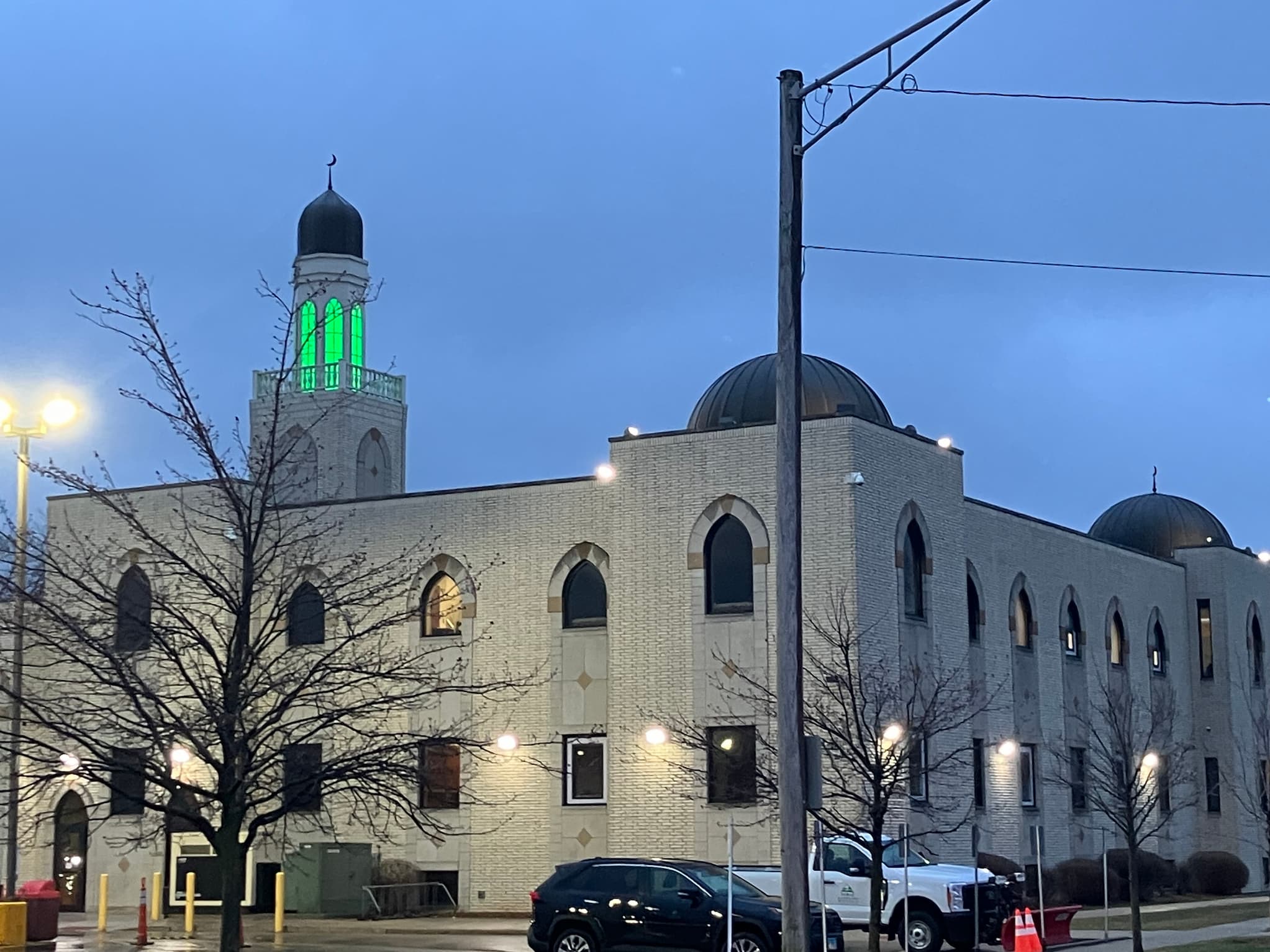 A mosque at dusk. The minaret emits a glowing green light.
