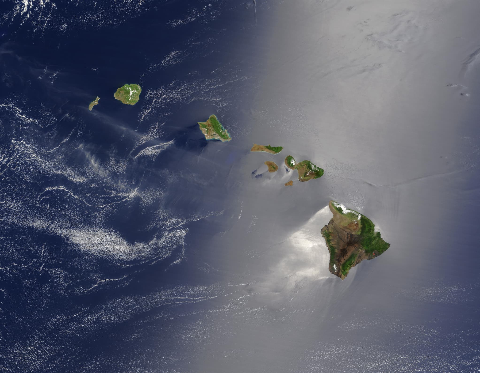 Ariel view showing the green islands of Hawaii and the movement of the ocean in the surrounding area.
