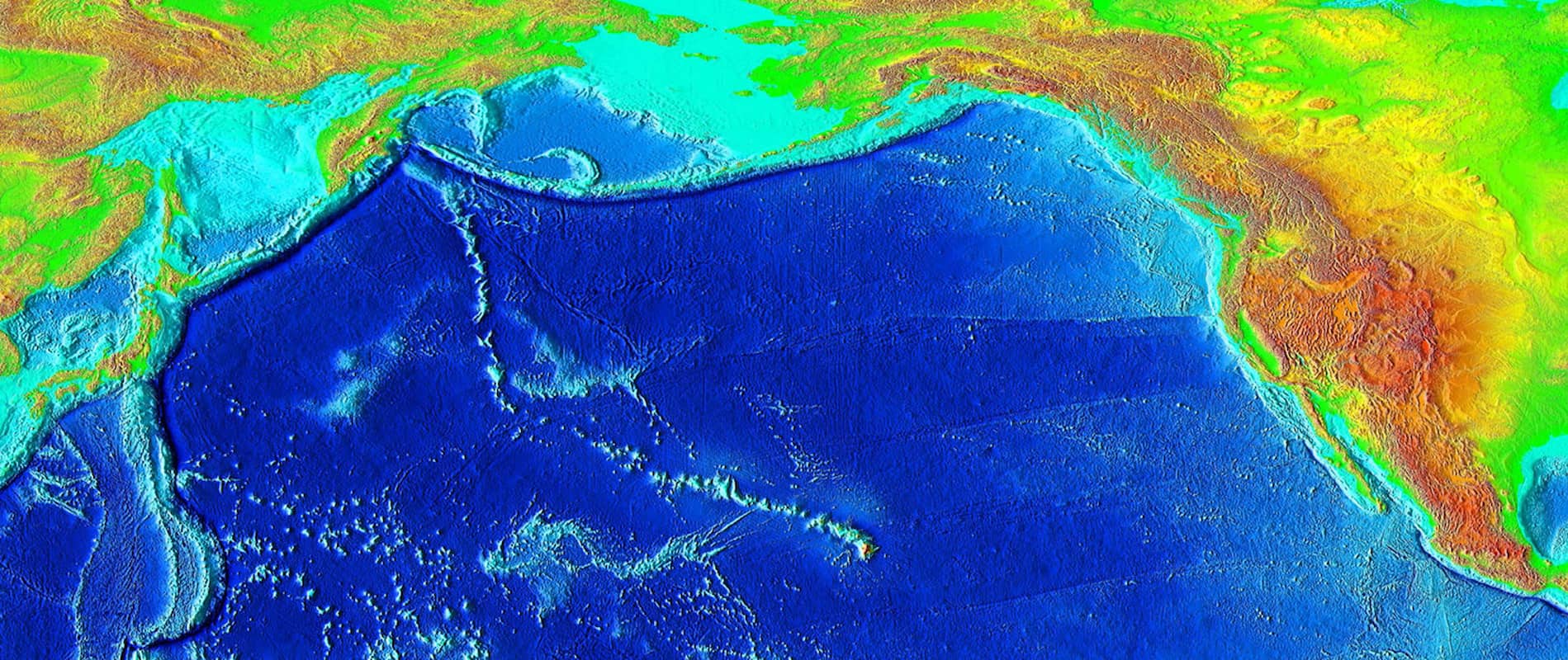 The map shows greens and oranges above the water. The ocean water is deep blue. The water along the coastline is teal.